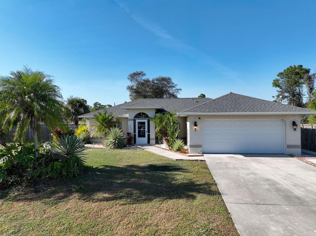 A single-story house with a white garage, a front walkway, and landscaping under a blue sky — 3357 N CHAMBERLAIN BOULEVARD, NORTH PORT, FL