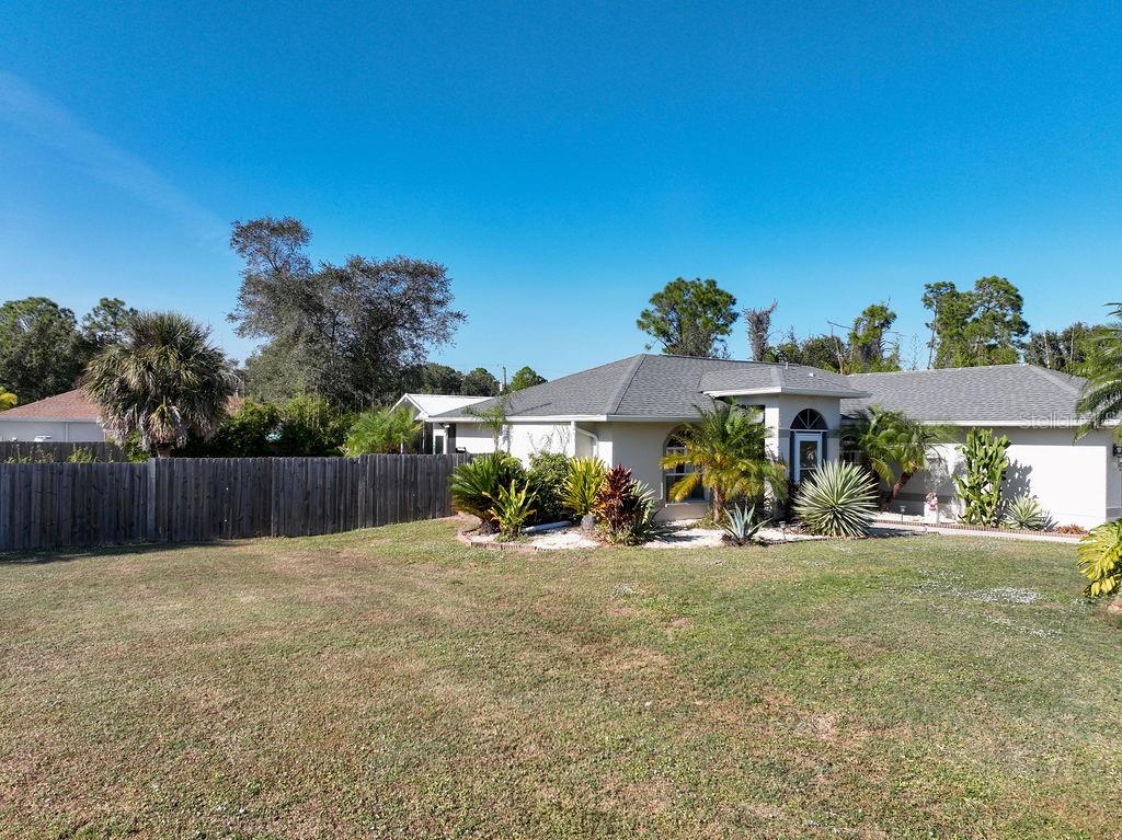 A single-story house with a light-colored exterior, a gray roof, and a fenced backyard — 3357 N CHAMBERLAIN BOULEVARD, NORTH PORT, FL