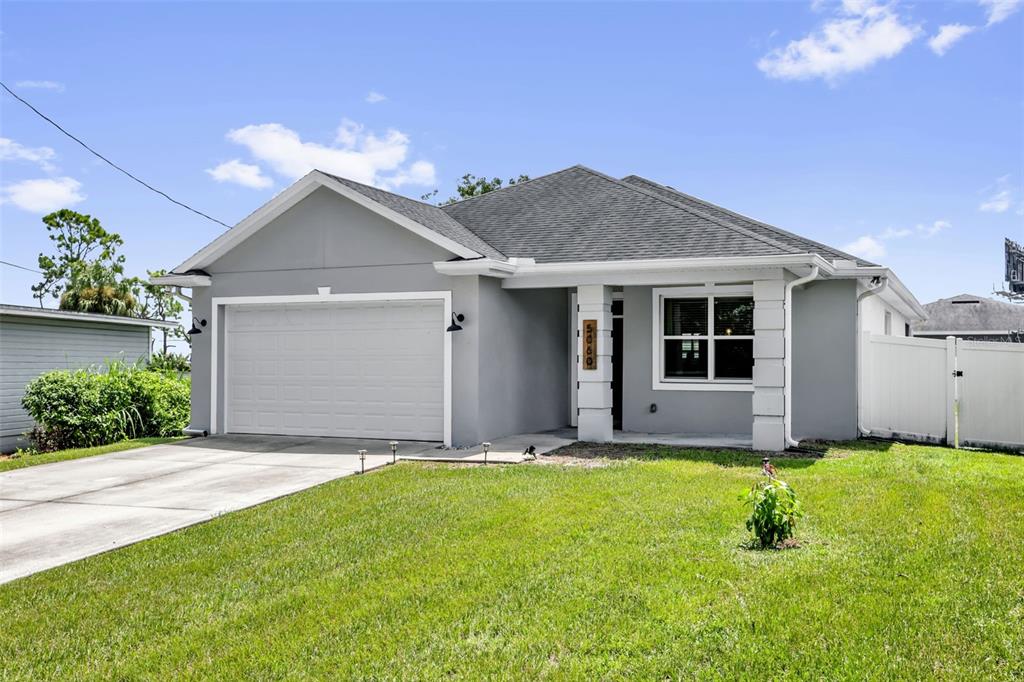 A single-story gray house with a two-car garage and a white vinyl fence — 5060 GYPSY LANE, ORLANDO, FL