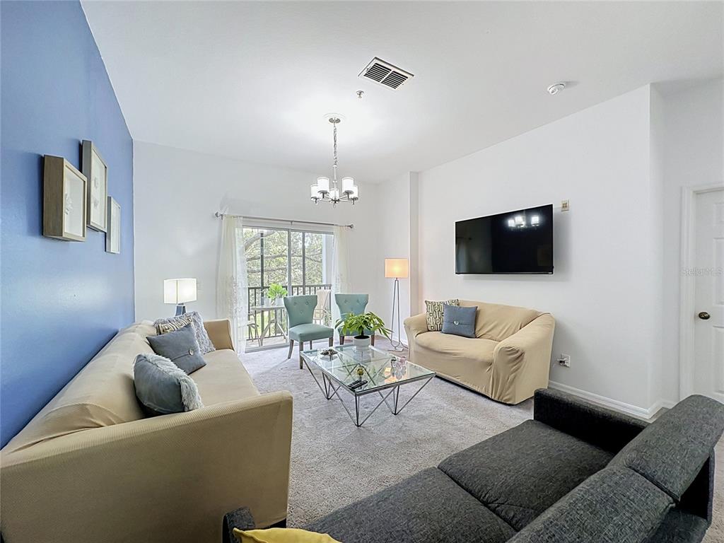 A living room features two beige sofas, a dark gray sofa, and a glass coffee table — 111 RUM RUN, DAVENPORT, FL