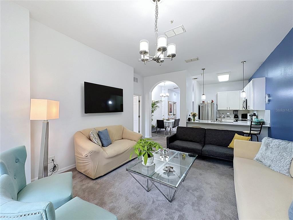 A living room with a glass coffee table, multiple sofas, and an open kitchen area — 111 RUM RUN, DAVENPORT, FL