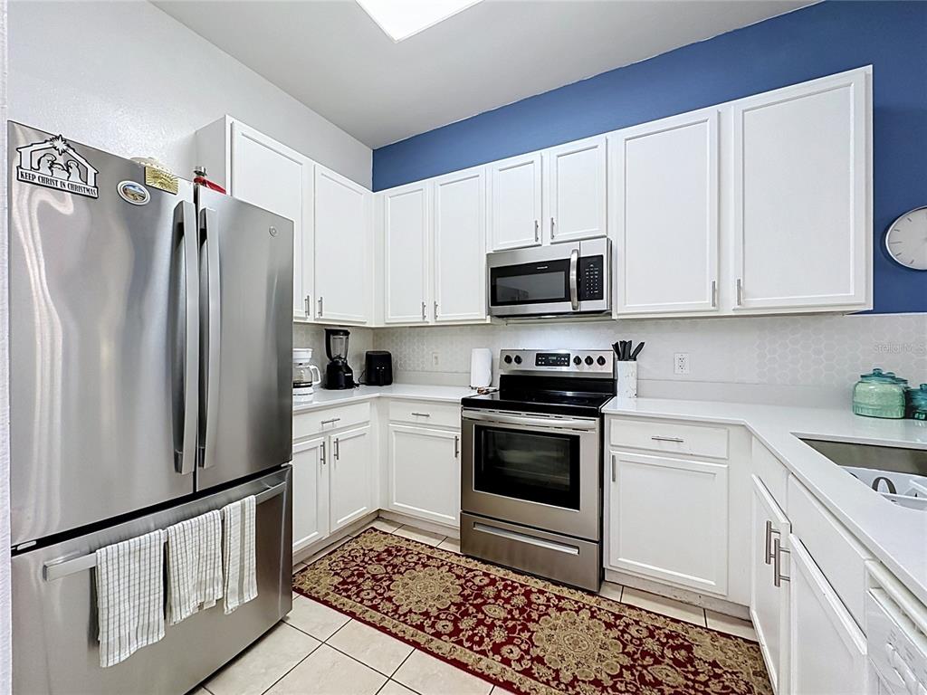 A kitchen features white cabinets, stainless steel appliances, a patterned rug, and blue wall accents — 111 RUM RUN, DAVENPORT, FL