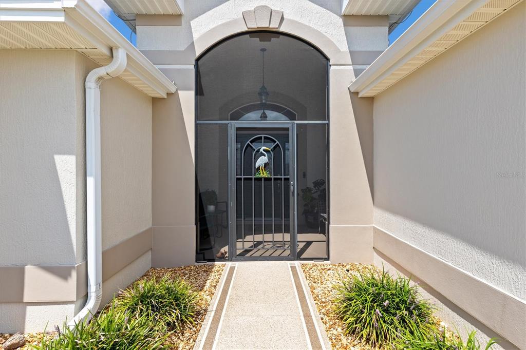 A front entryway features a screened door with a heron decoration and a concrete walkway — 1451 LUCKETT COURT, THE VILLAGES, FL