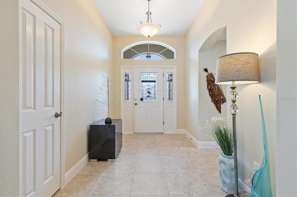 An entryway features a tiled floor, a white front door with sidelights, and a pendant light — 1451 LUCKETT COURT, THE VILLAGES, FL