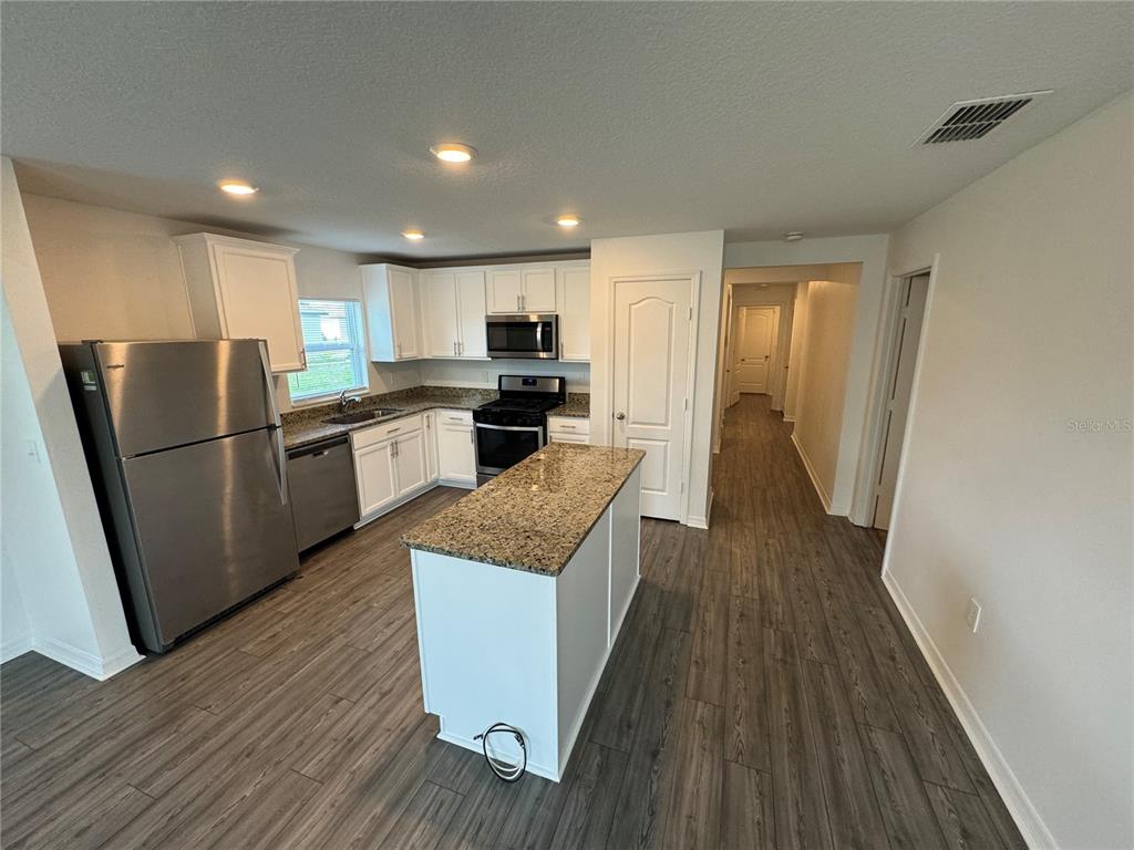 A kitchen features white cabinets, granite countertops, stainless steel appliances, and a central island — 233 KENSINGTON VIEW BOULEVARD, WINTER HAVEN, FL