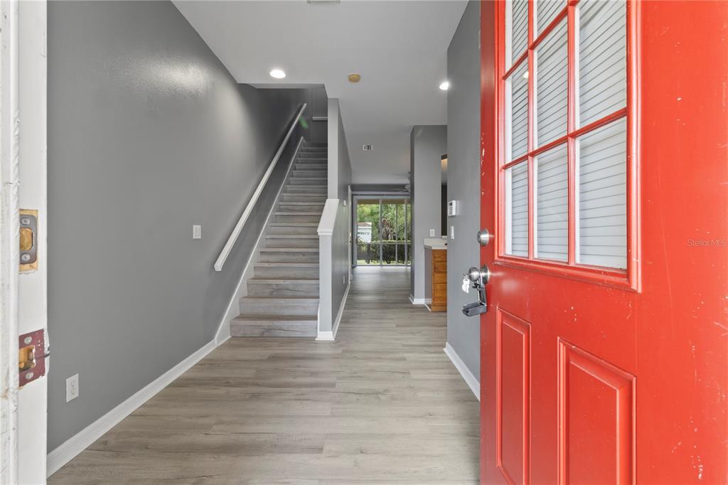 An entryway features gray walls, wood-look flooring, a staircase, and a bright red front door — 1147 JONAH DRIVE, NORTH PORT, FL