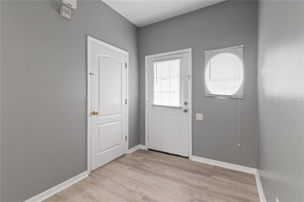 An interior room features gray walls, light wood-look flooring, two white doors, and a circular window — 1147 JONAH DRIVE, NORTH PORT, FL