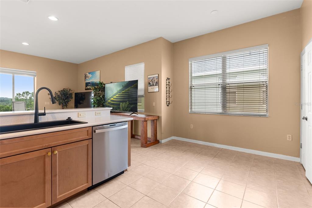 A kitchen with light wood cabinets, a stainless steel dishwasher, and a dining area — 2390 CALEDONIAN STREET, CLERMONT, FL