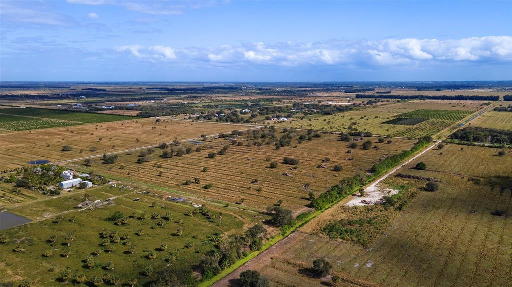 An aerial view shows a large, flat, rural landscape with scattered trees and open fields — 2321 SNEED ROAD, FORT PIERCE, FL