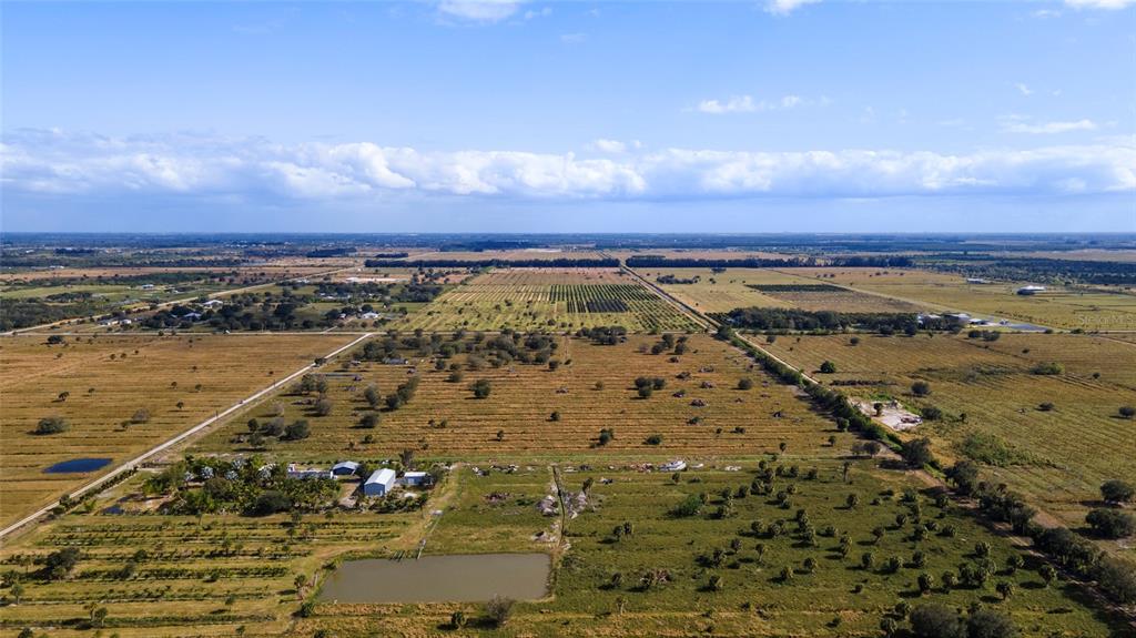 An aerial view shows a large, flat rural property with fields, scattered trees, and a pond — 2321 SNEED ROAD, FORT PIERCE, FL