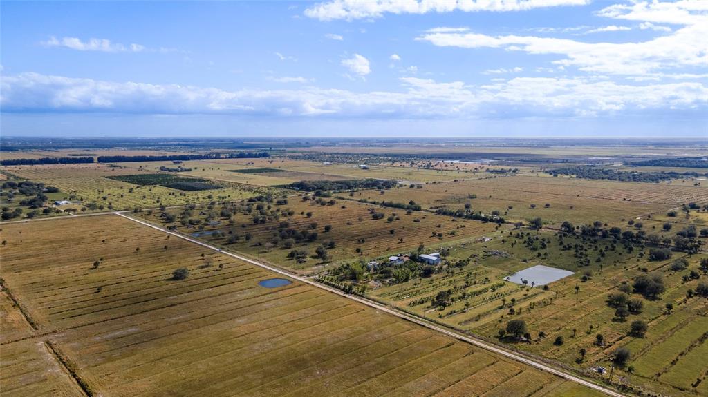 An aerial view shows a rural landscape with a road, scattered trees, and a small building — 2321 SNEED ROAD, FORT PIERCE, FL