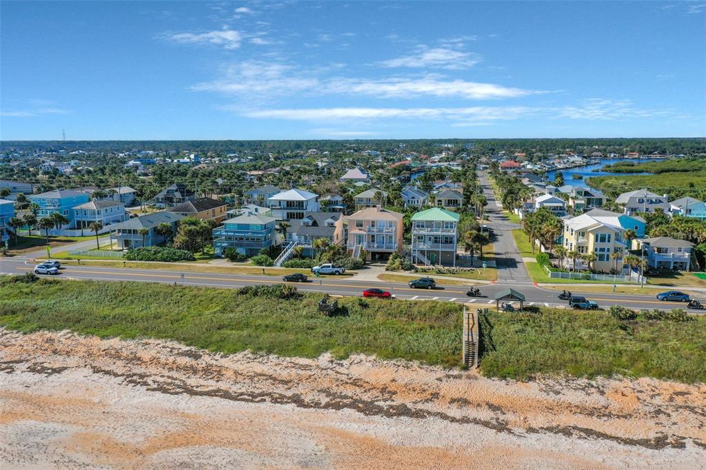 An aerial view shows a sandy beach, a coastal road, and several multi-story residential homes — N OCEAN BOULEVARD, FLAGLER BEACH, FL