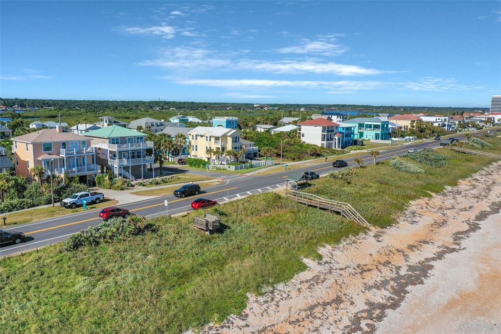 An aerial view shows a coastal road separating beach dunes from a residential neighborhood — N OCEAN BOULEVARD, FLAGLER BEACH, FL