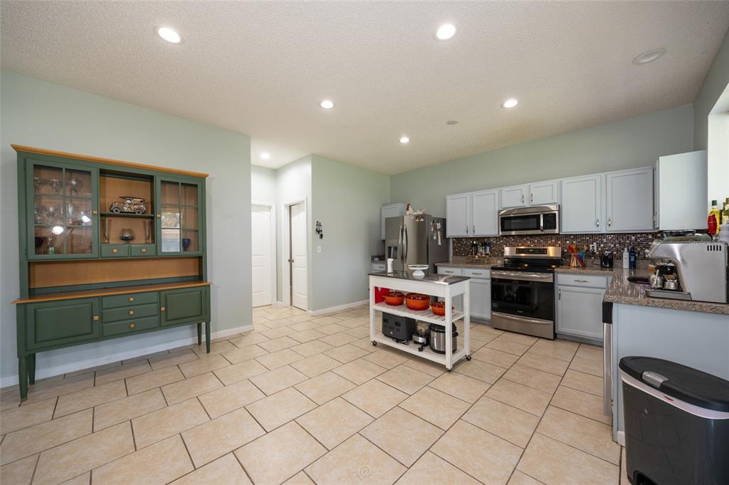 A kitchen features light blue cabinets, a green hutch, a center island, and tile flooring — 6 RYBARK LANE, PALM COAST, FL