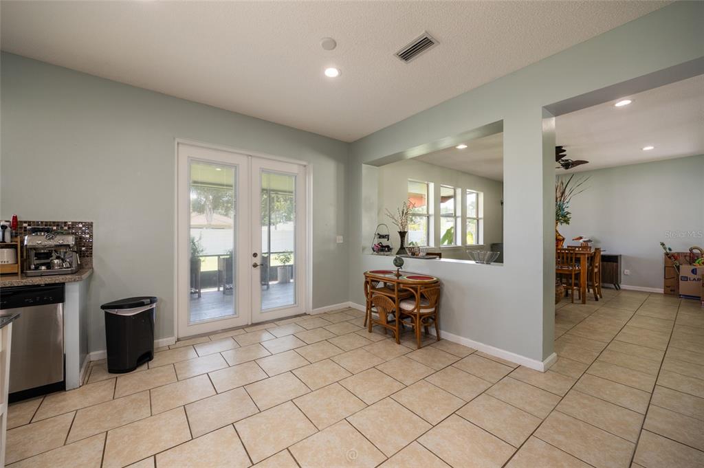 A kitchen and dining area with tile floors, a pass-through window, and glass patio doors — 6 RYBARK LANE, PALM COAST, FL