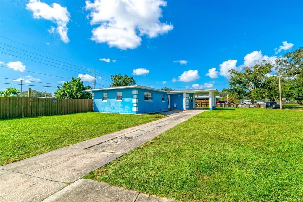 A blue single-story house with a flat roof and a concrete driveway under a blue sky — 804 ENGEL DRIVE, ORLANDO, FL