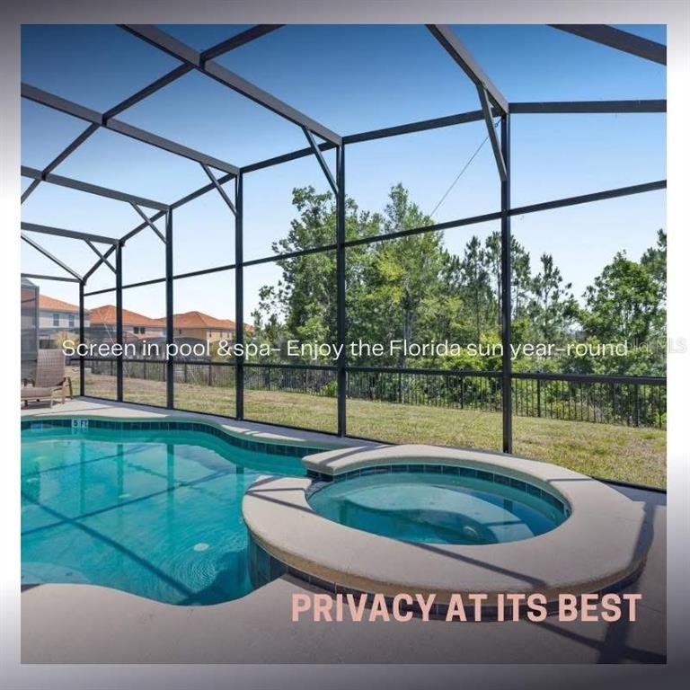 A screened-in swimming pool and hot tub overlook a grassy yard and distant houses — 411 CABELLO DRIVE, DAVENPORT, FL