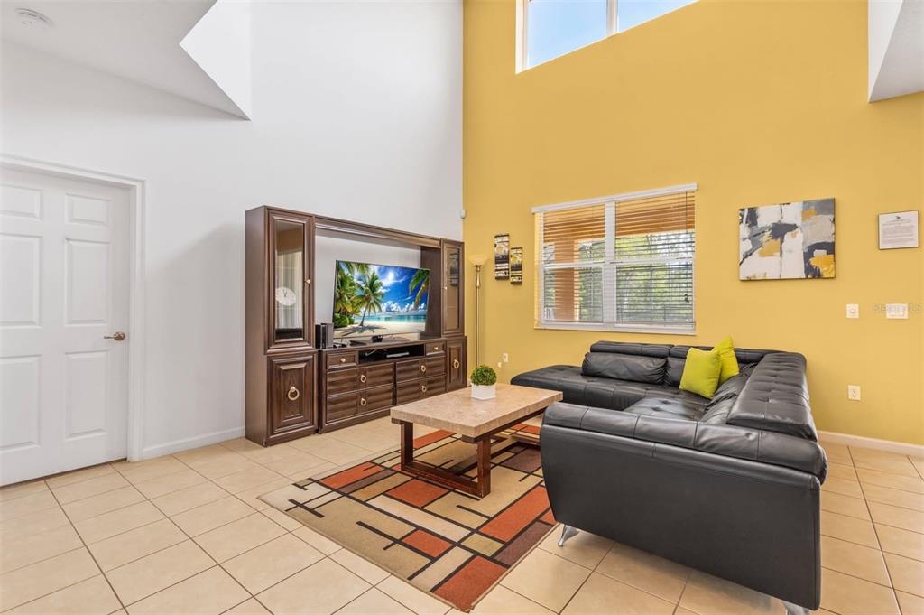 A living room features a black sectional sofa, a large entertainment center, and yellow walls — 411 CABELLO DRIVE, DAVENPORT, FL