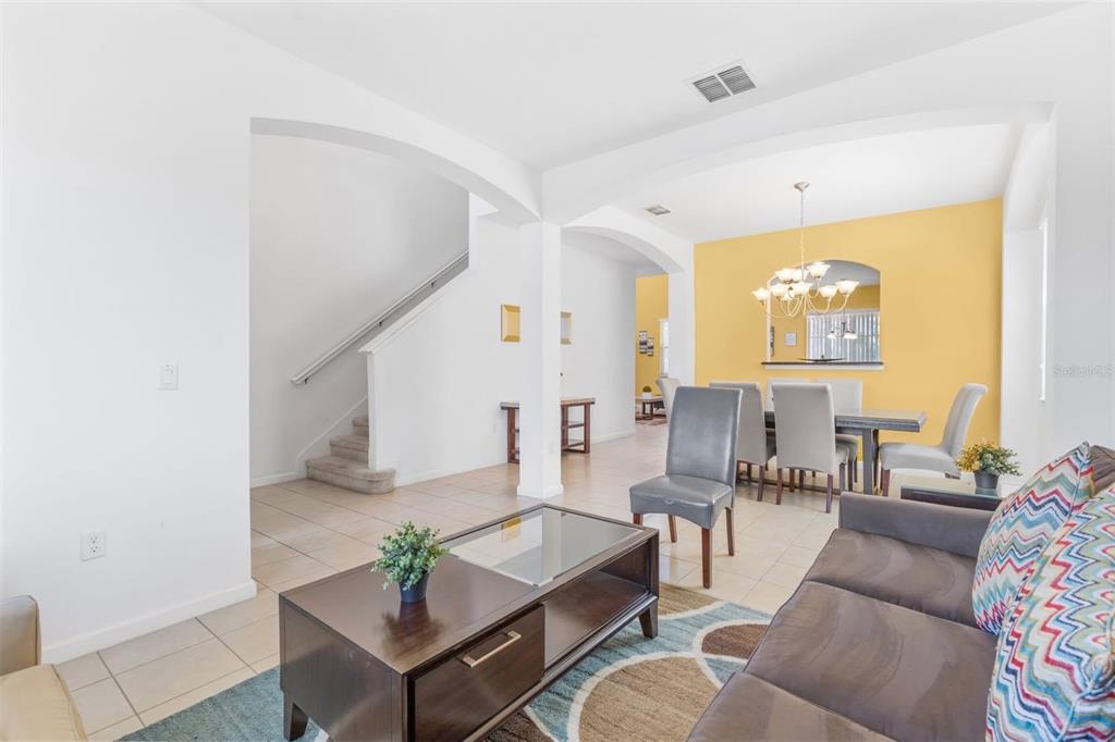 A living room with tile floors leads to a dining area with a yellow wall — 411 CABELLO DRIVE, DAVENPORT, FL