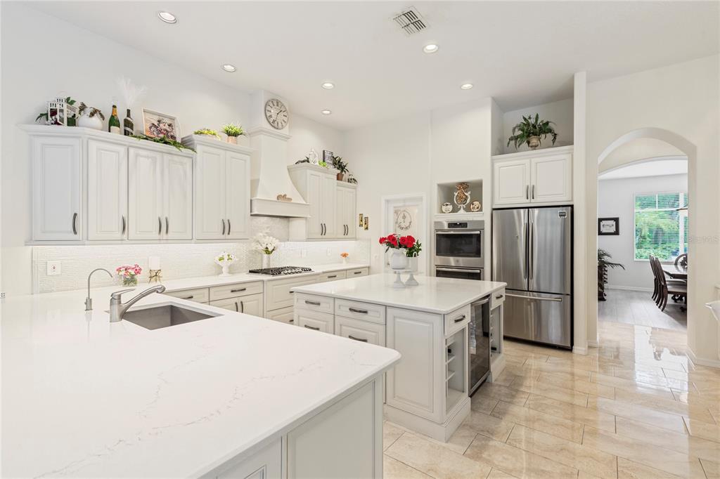 A bright, modern kitchen features white cabinetry, a large central island, and stainless steel appliances — 5603 EAGLEGLEN PLACE, LITHIA, FL