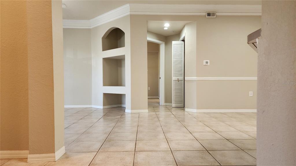 An interior view of a room with tiled floors, a built-in arched niche, and doorways — 5134 NORTHRIDGE ROAD UNIT 203, SARASOTA, FL