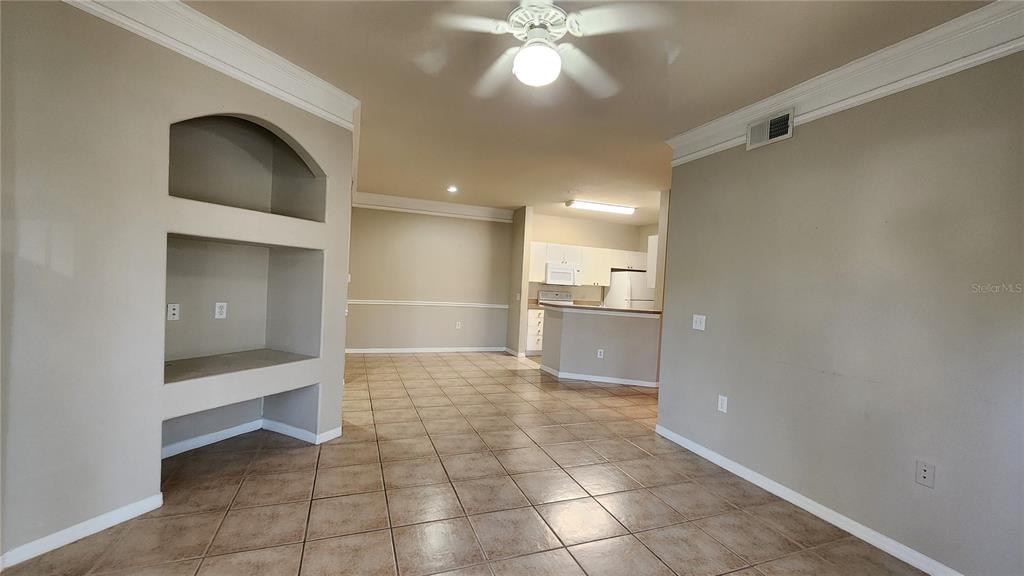 An interior view shows a tiled living area with a built-in niche and open kitchen — 5134 NORTHRIDGE ROAD UNIT 203, SARASOTA, FL