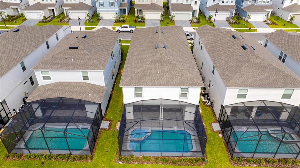 An aerial view shows three suburban houses with screened-in swimming pools in their backyards — 3325 LILAC WAY, DAVENPORT, FL
