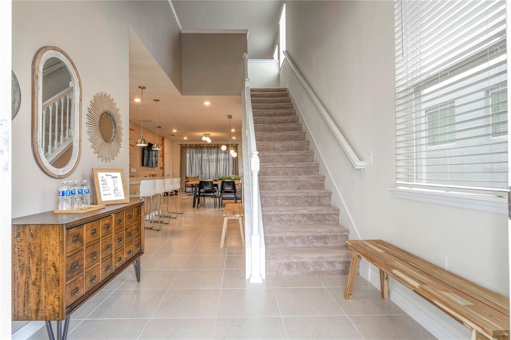 An entryway with a wooden console table, a staircase, and a view into the dining area — 3325 LILAC WAY, DAVENPORT, FL