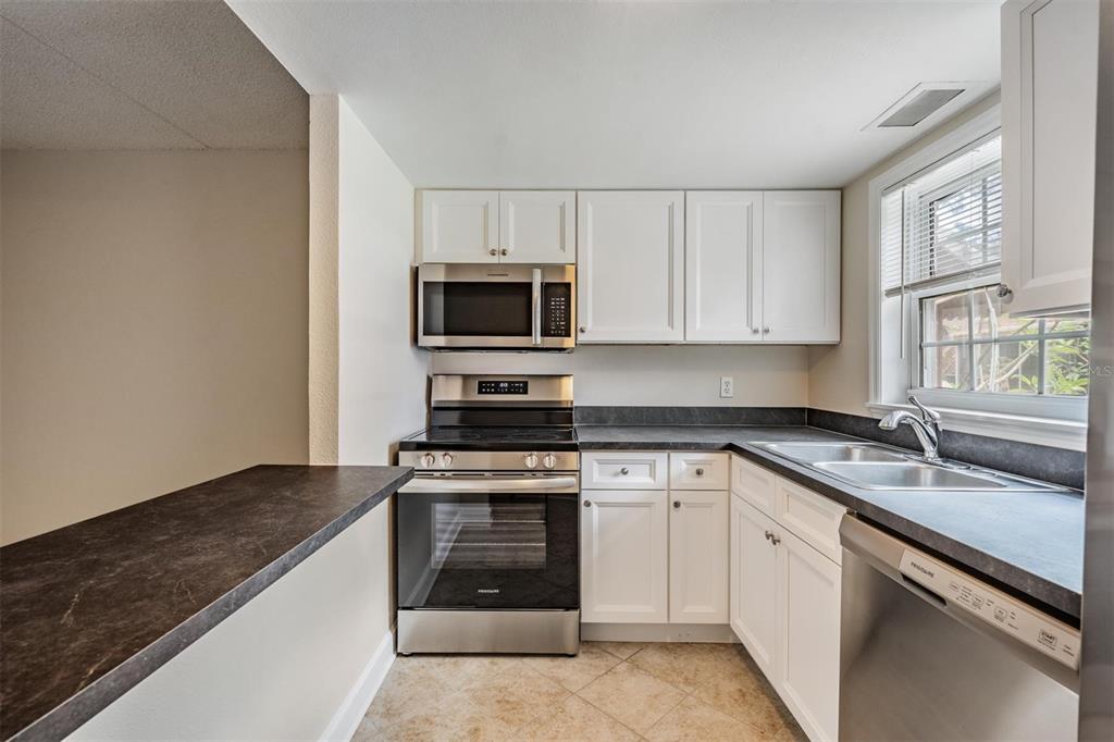 An aerial view shows a rectangular swimming pool and a tennis court next to parking — 8565 12TH WAY N UNIT A, ST PETERSBURG, FL