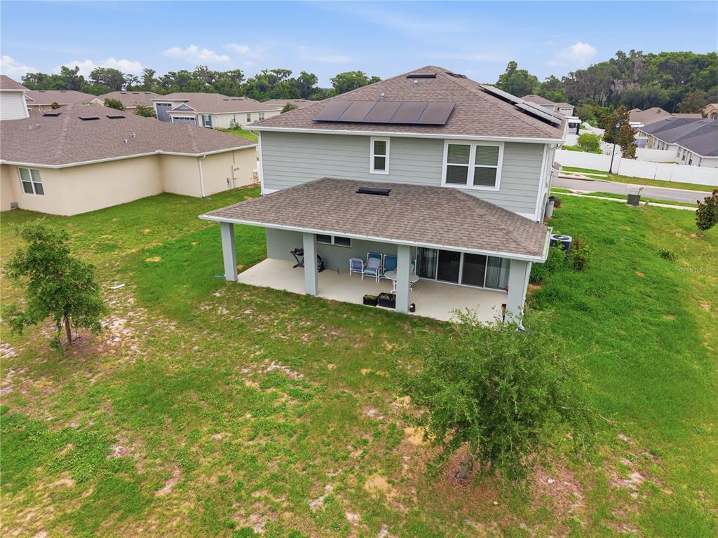 A two-story house with a covered patio, solar panels on the roof, and a grassy yard — 31707 BROADWATER AVENUE, LEESBURG, FL