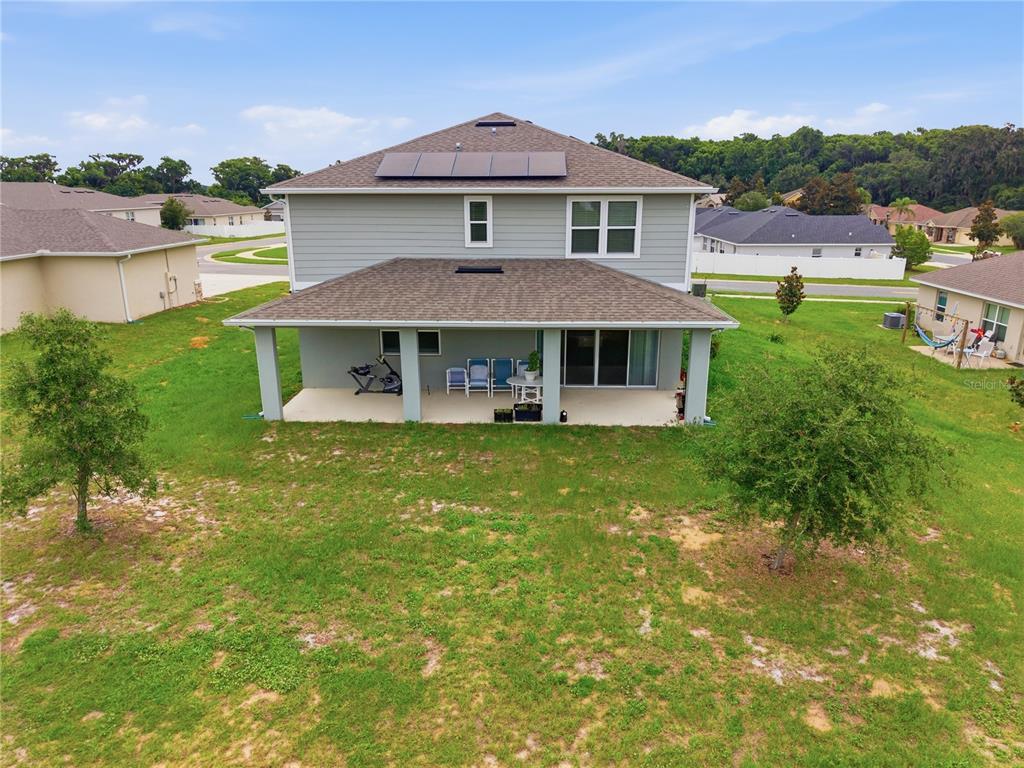 The rear exterior of a two-story house features a covered patio and solar panels — 31707 BROADWATER AVENUE, LEESBURG, FL