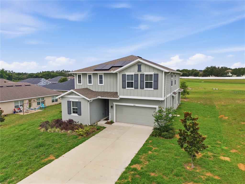 An aerial view shows a two-story house with light green siding, a garage, and solar panels — 31707 BROADWATER AVENUE, LEESBURG, FL