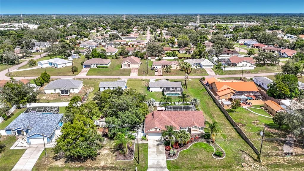 An aerial view shows a residential neighborhood with single-family homes, green lawns, and swimming pools — 1388 HASTINGS ROAD, SPRING HILL, FL