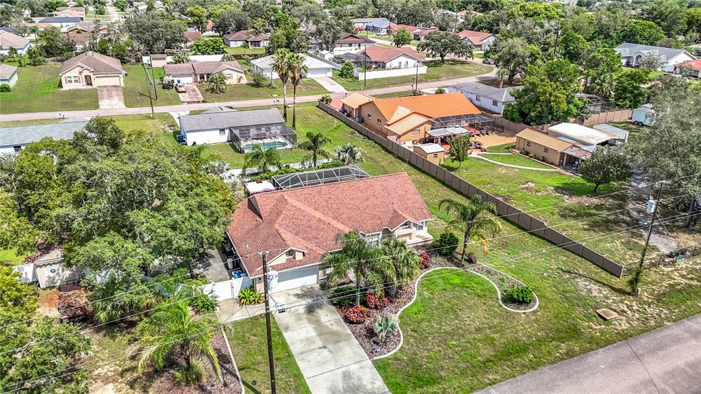 An aerial view shows a suburban house with a brown roof, driveway, and large yard — 1388 HASTINGS ROAD, SPRING HILL, FL