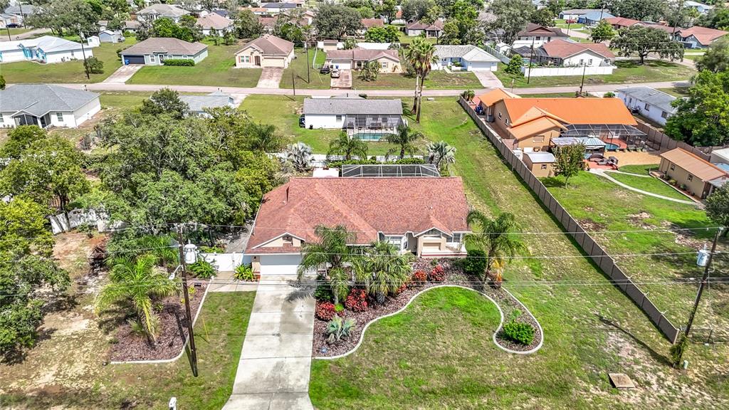 An aerial view shows a single-story house with a brown roof and a screened pool — 1388 HASTINGS ROAD, SPRING HILL, FL