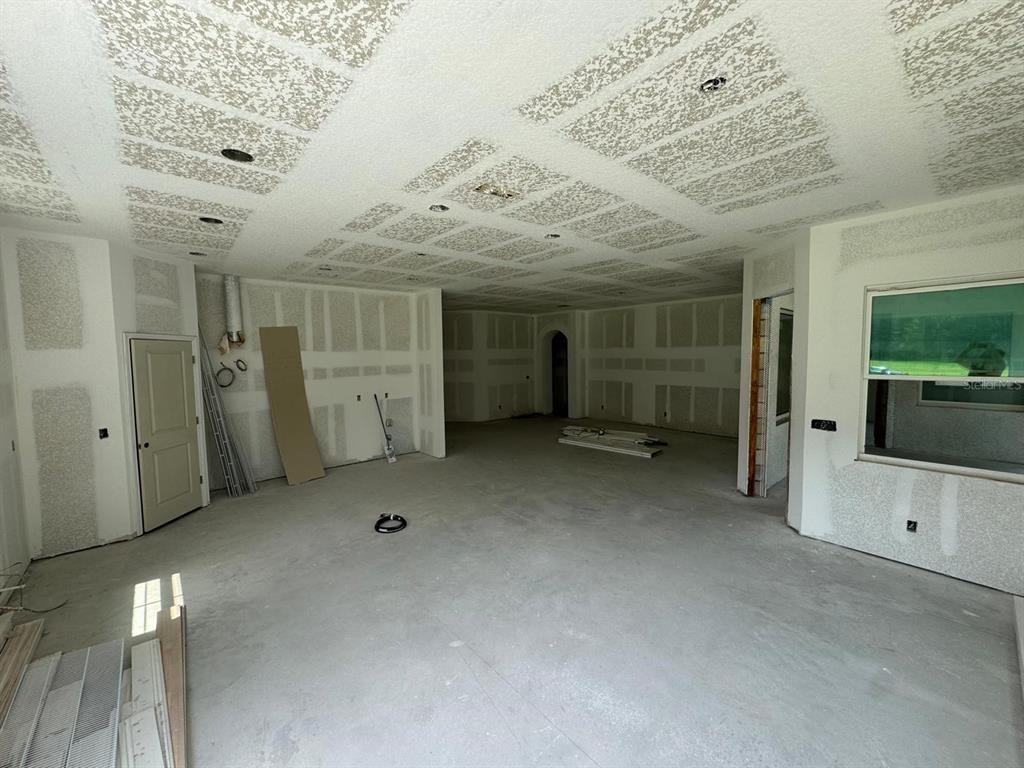 An unfinished room features drywall walls, a textured ceiling with recessed lighting, and concrete flooring — 6701 OLD MELBOURNE HIGHWAY UNIT A, ST CLOUD, FL
