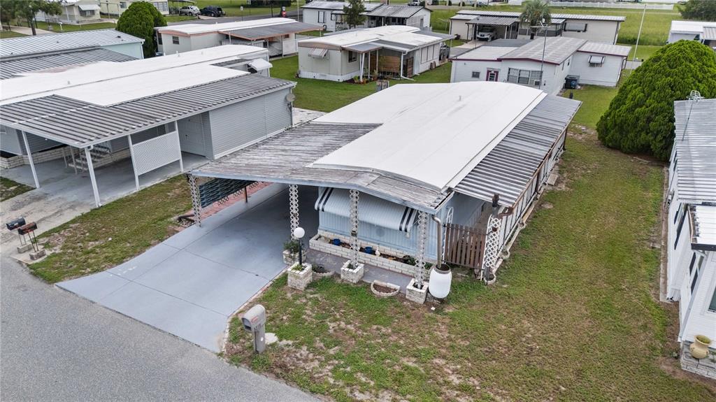 An aerial view shows a mobile home with a carport and a metal roof — 5318 ASTRID DRIVE, ZEPHYRHILLS, FL