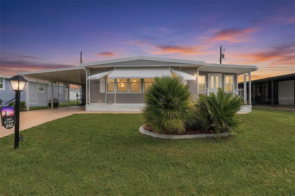 A single-story manufactured home with a carport and a small front yard at sunset — 652 LA SALA, NORTH PORT, FL