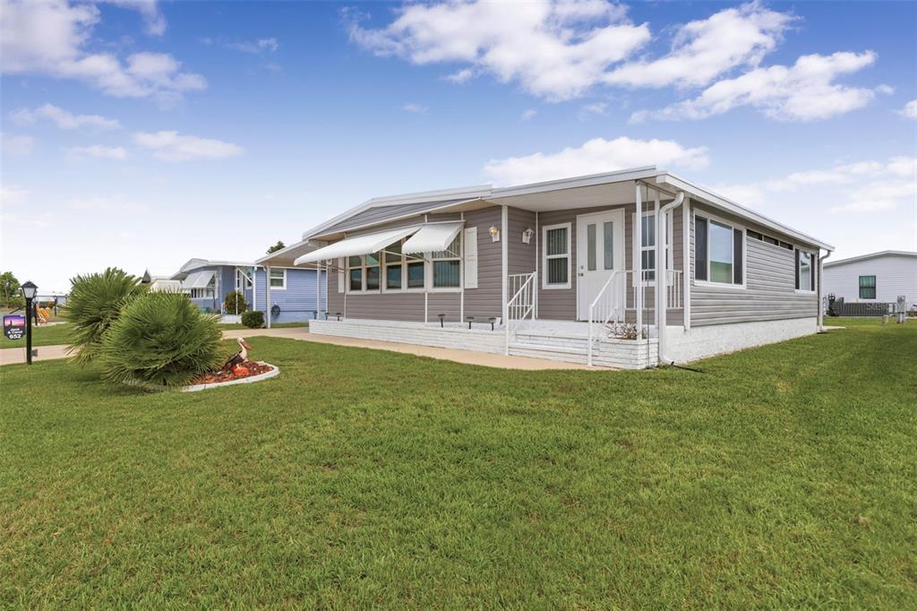 A single-story manufactured home with grey siding and a white brick foundation sits on grass — 652 LA SALA, NORTH PORT, FL