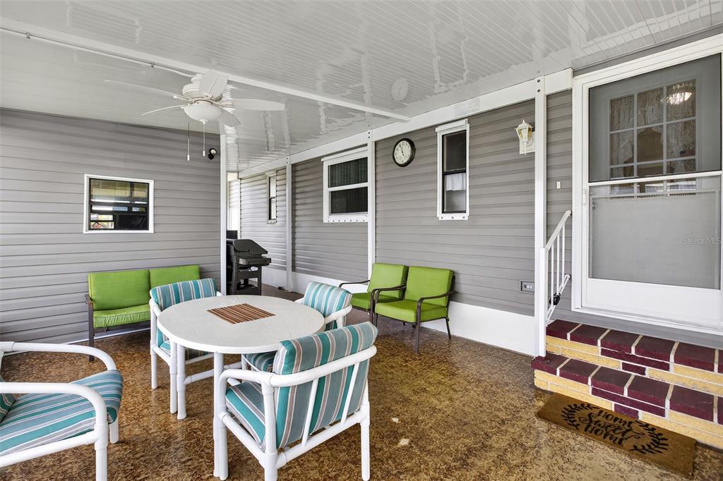 A covered patio features a dining set, green chairs, and a door with steps — 652 LA SALA, NORTH PORT, FL