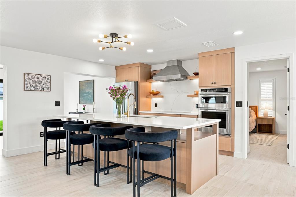 An open-concept living room and kitchen featuring a brown sectional, brick wall, and island — 6241 TANGLEWOOD DRIVE NE, ST PETERSBURG, FL