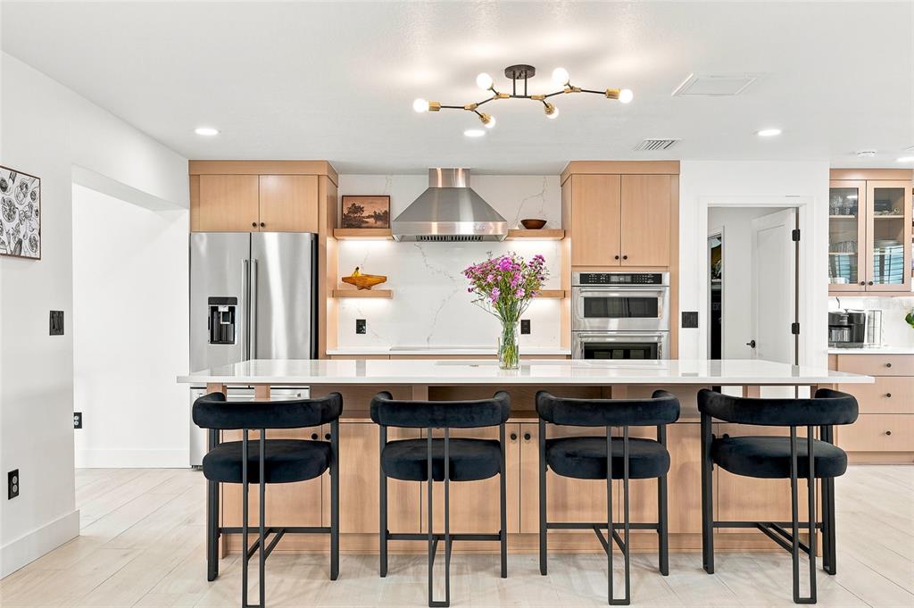 An open-concept living room and kitchen featuring a large sectional sofa and wood-look flooring — 6241 TANGLEWOOD DRIVE NE, ST PETERSBURG, FL