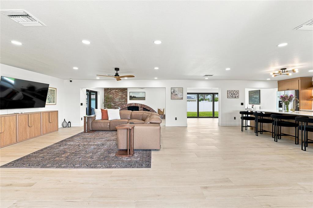 An open-concept living room features light wood floors, a brick fireplace, and a kitchen island — 6241 TANGLEWOOD DRIVE NE, ST PETERSBURG, FL