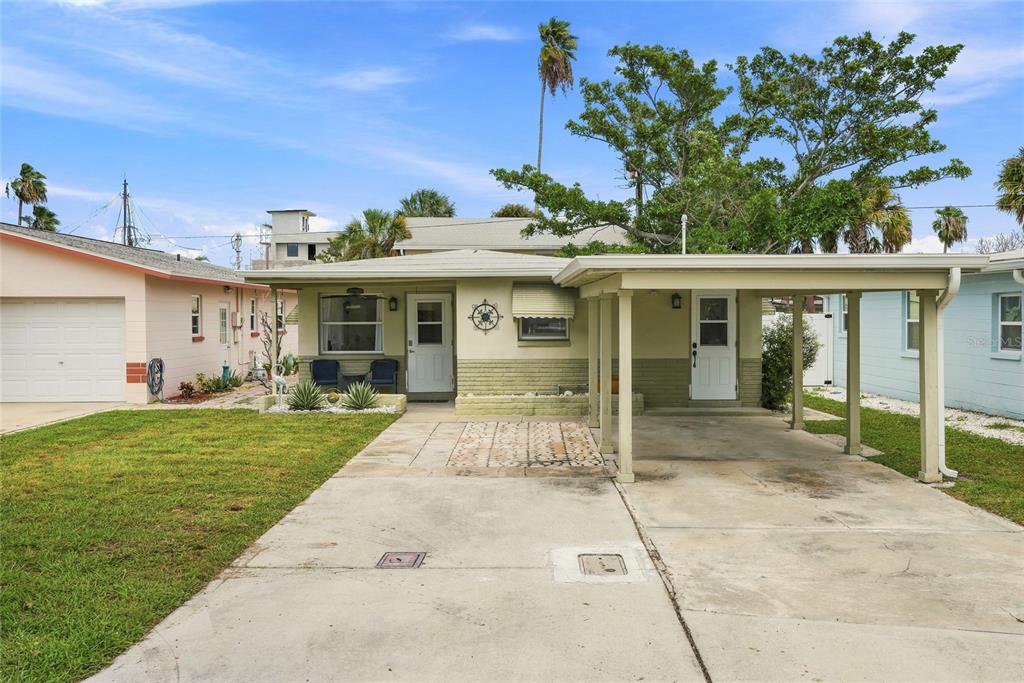 A single-story house with a carport, concrete driveway, and light green exterior siding — 13313 2ND STREET E, MADEIRA BEACH, FL