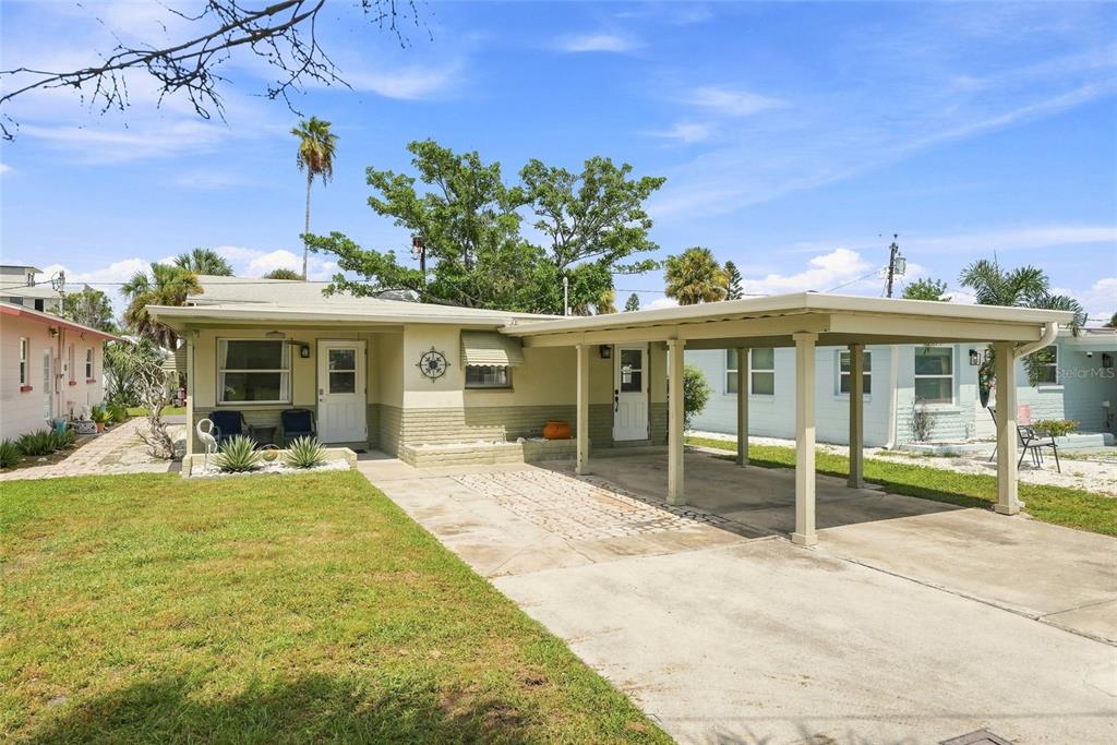 A one-story house with a carport, a grassy lawn, and light-colored exterior siding — 13313 2ND STREET E, MADEIRA BEACH, FL