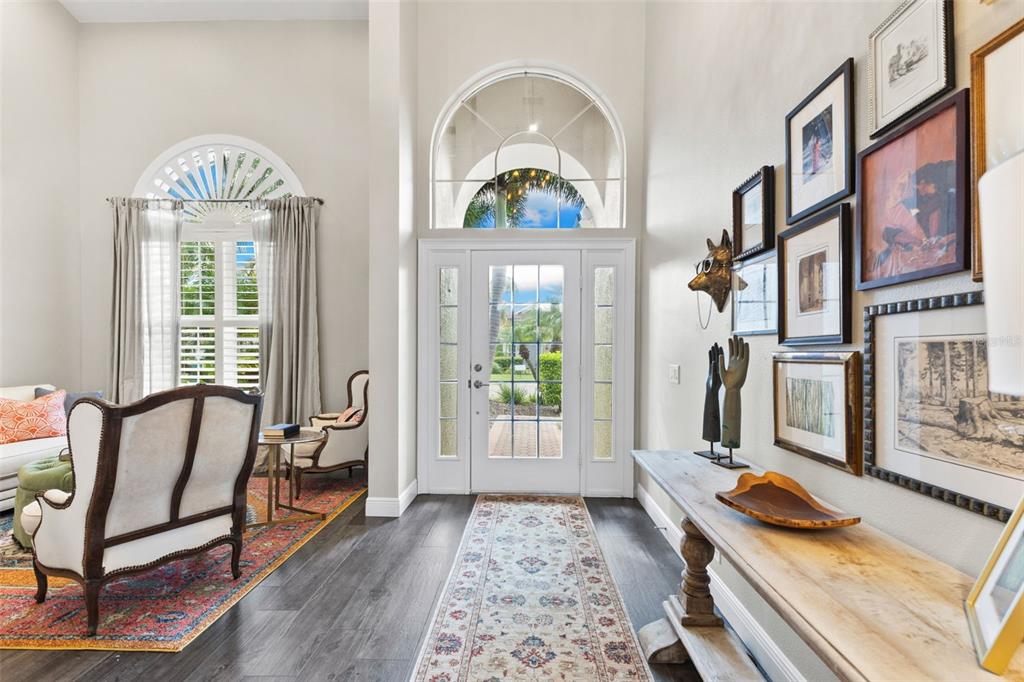 A bright entryway features a white front door, arched windows, dark flooring, and gallery walls — 304 9TH AVENUE E, PALMETTO, FL
