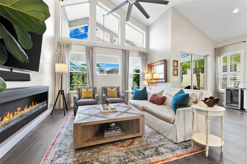 A living room features a fireplace, vaulted ceilings, large windows, and a wooden coffee table — 304 9TH AVENUE E, PALMETTO, FL