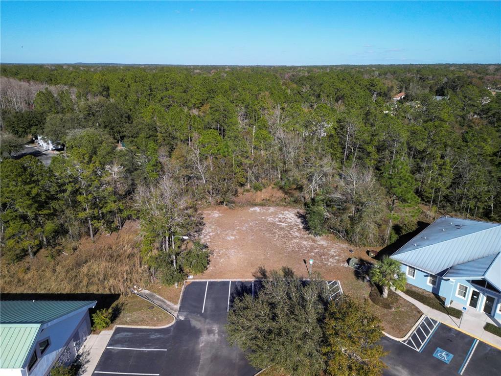 An aerial view shows a cleared, rectangular vacant lot situated between two commercial buildings — 8401 S SUNCOAST BOULEVARD UNIT 3, HOMOSASSA, FL
