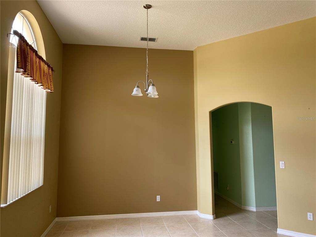 A dining room with high ceilings, a chandelier, arched entryway, and tile flooring — 12934 COLONNADE CIRCLE, CLERMONT, FL