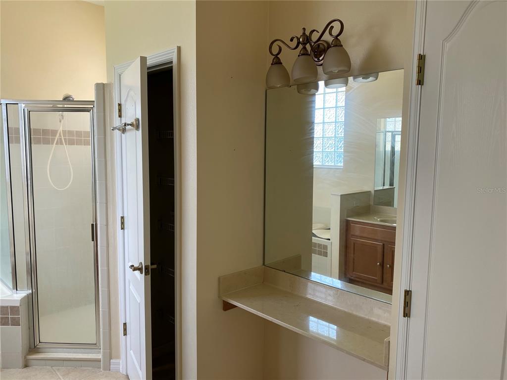 A bathroom features a vanity with a mirror, a glass-enclosed shower, and a closet door — 12934 COLONNADE CIRCLE, CLERMONT, FL